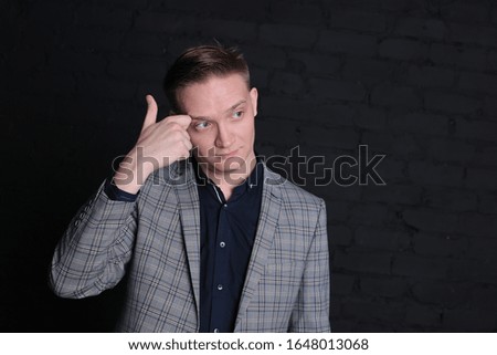 portrait emotional stylish young man in a jacket and shirt on a dark background
