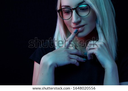 pensive young Caucasian beautiful blonde woman with glasses . close-up portrait in neon light
