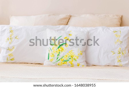 There are many pillows of white and beige colors on the bed.