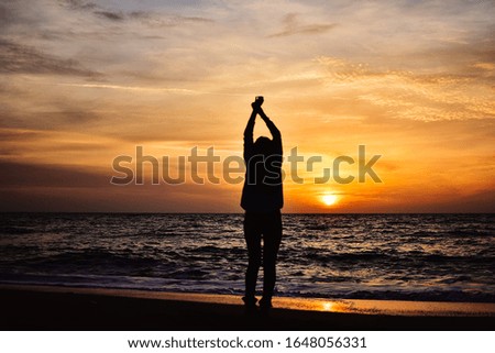 dancing girl in front of sunrise sky at the sea with stunning colors