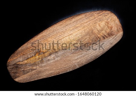 Stock photo of a natural oval wooden board on a black background.