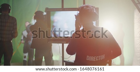 Medium shot of a director giving instructions on a walkie-talkie during the shooting of a scene