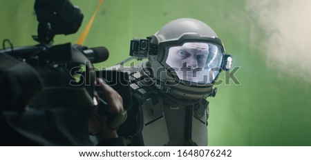 Medium shot of a cameraman filming a sci-fi scene with a astronaut looking around