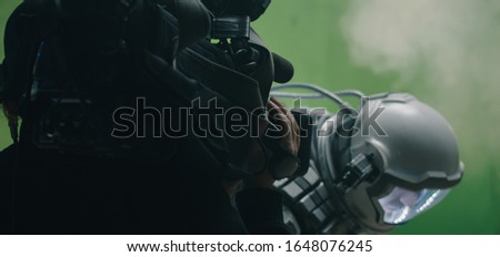 Medium shot of a cameraman filming a sci-fi scene with a astronaut looking around