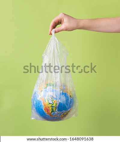 no plastic concept. hands holding planet earth globus in plastic bag. eco concept on green background