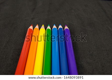     seven colored pencils in a row on a black background                           