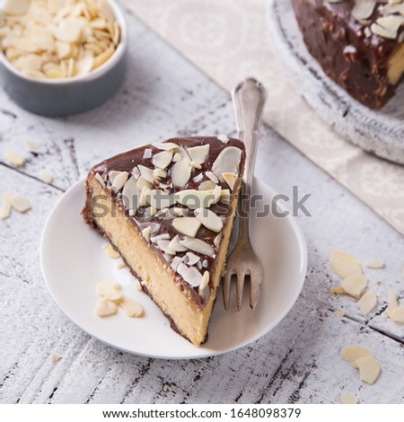 Piece Slice of Сheesecake with Chocolate, Caramel, Peanut Paste, Nougat Layered Cake on white table background