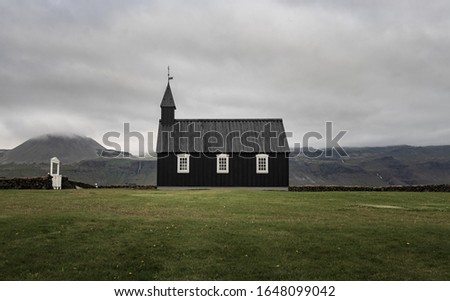 a picture of the famous black church in Budir, Iceland, taken on a cloudy day in toned down colors.
