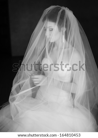 Young caucasian bride at home waiting for groom. Black and white picture.