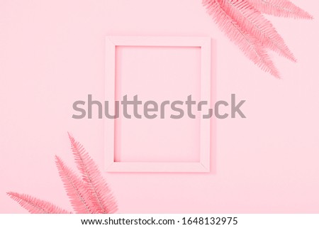 Elegant pink background. Blank photo frame, tropical pink leaves on pastel pink background. Flat lay, top view, copy space