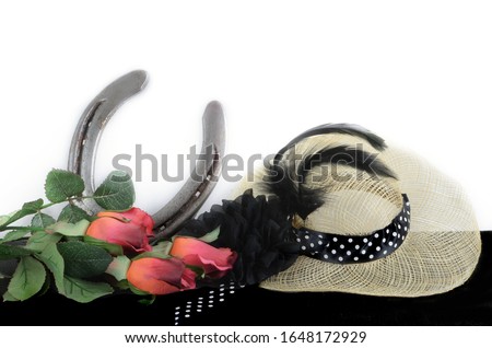 Kentucky Derby photo of a fascinator hot with red roses and a horseshoe. on a black table with white background Royalty-Free Stock Photo #1648172929