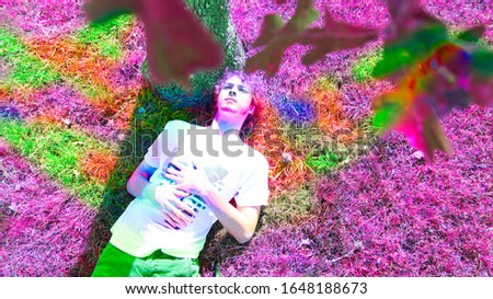 Aerial view of man laying under tree with multicolored grass and leaves Royalty-Free Stock Photo #1648188673