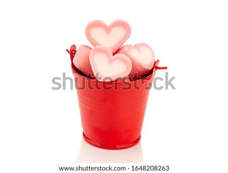 Marshmallows heart shaped in a red iron bucket on white background with clipping path. 
