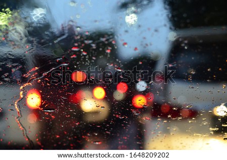 Abstract bokeh balls from cars rear light, photographed through a car windshield during rain.