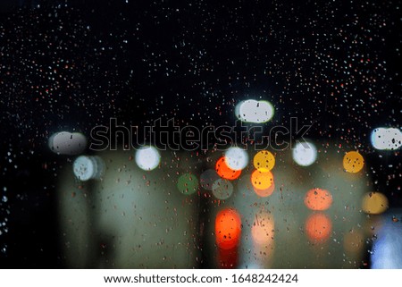 Blurred city street with waterdrops, neon lights car background