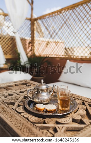Traditional moroccan mint tea with cookies on silver tray on carved wooden table. Beautiful vintage style, hospitality in Morocco.