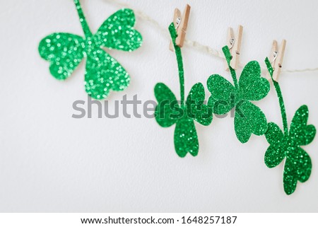 Happy St. Patricks day. Green glitter shamrocks decoration. Homemade garland of rope and clover leaves on clothespins.