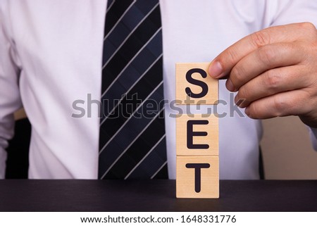 Businessman made word SET with wood building blocks.
