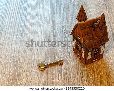 Model of a house and golden key On Wooden Table. Real estate agency, mortgage loan, lottery, buying property.Home loan and investment concept. Copy space
