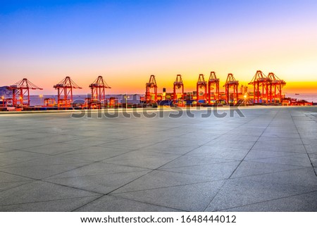 Empty square floor and industrial container terminal at beautiful sunset in Shanghai.