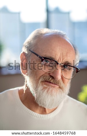 Positive man. Close up picture of grey-haired bearded man in eyewear smiling nicely