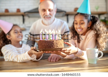 Bday cake. Two dark-skinned girls holding his grandads birthday cake