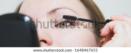 Girl is applying makeup. Black mascara on eyelashes. Beauty photo concept.