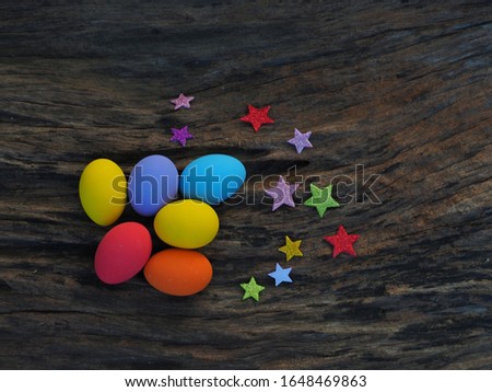 Top view colorful eggs on wooden background with paper star, Easter festival.