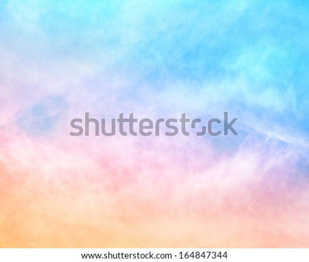 A soft cloud background with a pastel colored orange to blue gradient.  Image features a pleasing paper grain and texture at 100 percent.