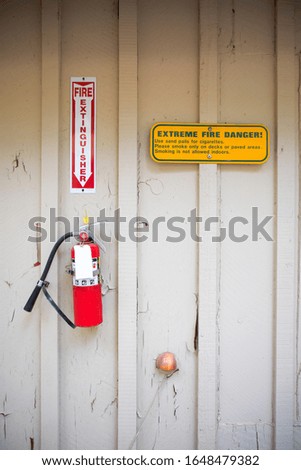 A wall mounted fire extinguisher outsid the building near the fire exit