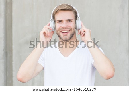 Wireless Earpiece. Handsome guy wear headphones grey background. Man listen modern music. Modern technology. Hobby leisure. Foldable Stereo Headphones. Noise Reduction. Modern and contemporary music.