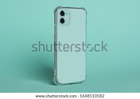 Phone case mock up side view. Mint green iPhone 11 in clear silicone case isolated on green background, rotated position. Smartphone perspective view