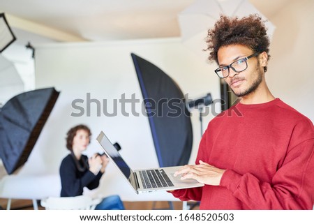 Photographer with Laptop Computer makes backup at the photo shoot
