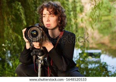 Young photographer with camera and tripod as nature photographer or wildlife photographer