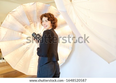 Smiling photographer with medium format camera in front of studio light in the photo studio