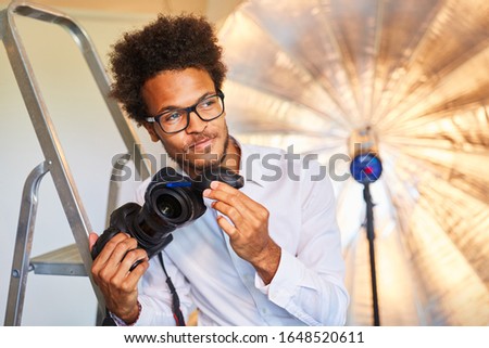 Young photographer or photo assistant at the lens cleaning in the photo studio