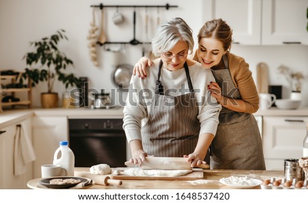 happy family grandmother  old mother mother-in-law and daughter-in-law daughter cook in kitchen, knead dough and bake cookies Royalty-Free Stock Photo #1648537420