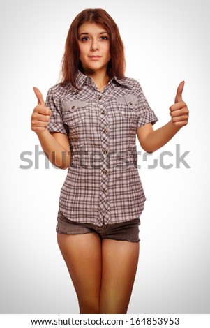 young woman brunette girl shows positive sign thumbs yes, shirt shorts isolated emotion 