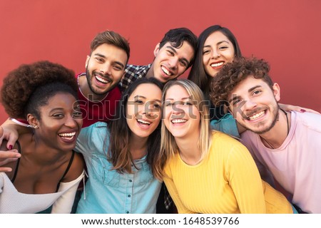 Group multiracial people having fun outdoor - Happy mixed race friends sharing time together - Youth millennial generation and multiethnic teenagers lifestyle concept - Red Background Royalty-Free Stock Photo #1648539766