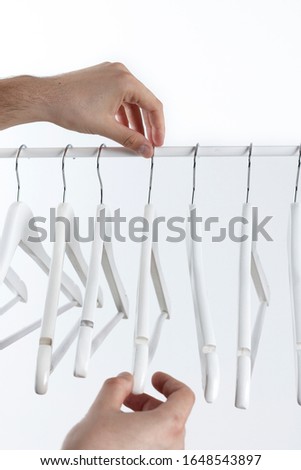 Hand holding empty clothes hanger against white background
