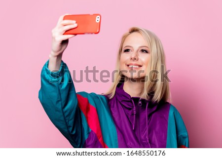 Beautiful blonde woman make selfie on pink background