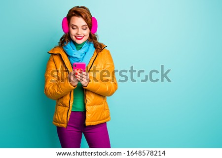 Photo of pretty traveler lady hold telephone search look map user navigation system wear trendy casual yellow overcoat scarf purple trousers isolated teal color background