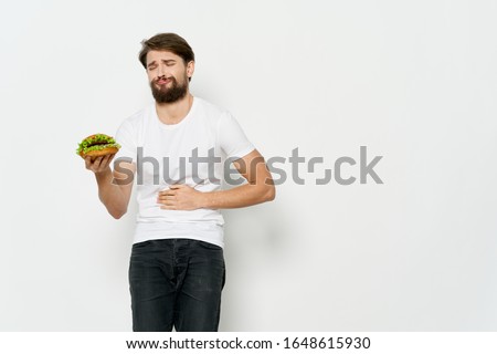 A man in a white T-shirt hamburger fast food diet food meal restaurant