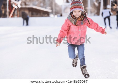 Cute little girl ice skating on a rink in the city center