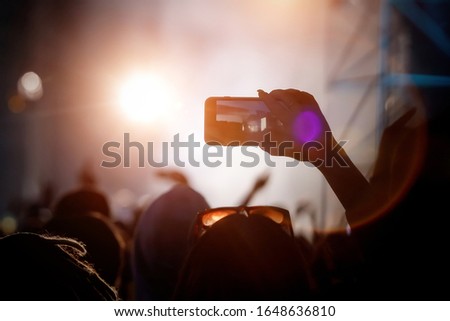 Girl using smartphone to take a video at a concert.
