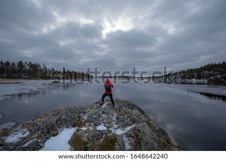 tourist in a red jacket on the background of a beautiful landscape. Photographer on the shore of lake Ladoga