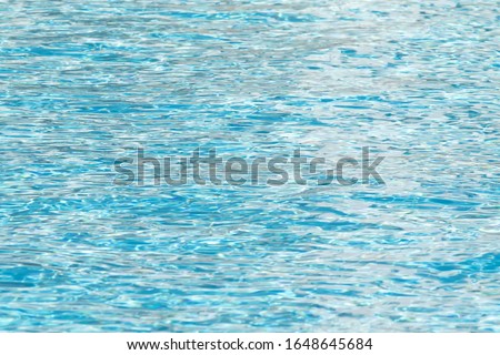 Water surface background. Blue pool water with sun reflections. Ripples of water in the pool.