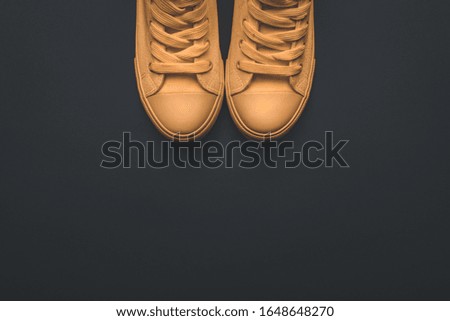 Modern yellow canvas sneakers on dark background, top view flat lay with copy space