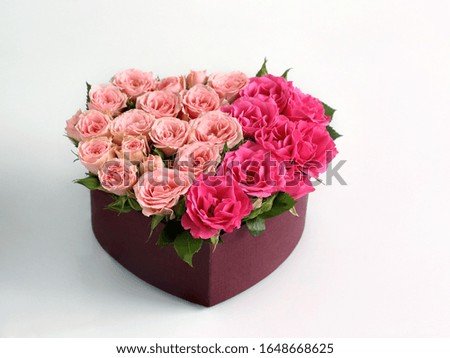 a bouquet of pink roses in a heart-shaped box on a white table, close-up with a blurred background. as a gift for March 8 or birthday