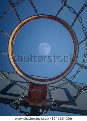 Full moon rising above the basketball basket.